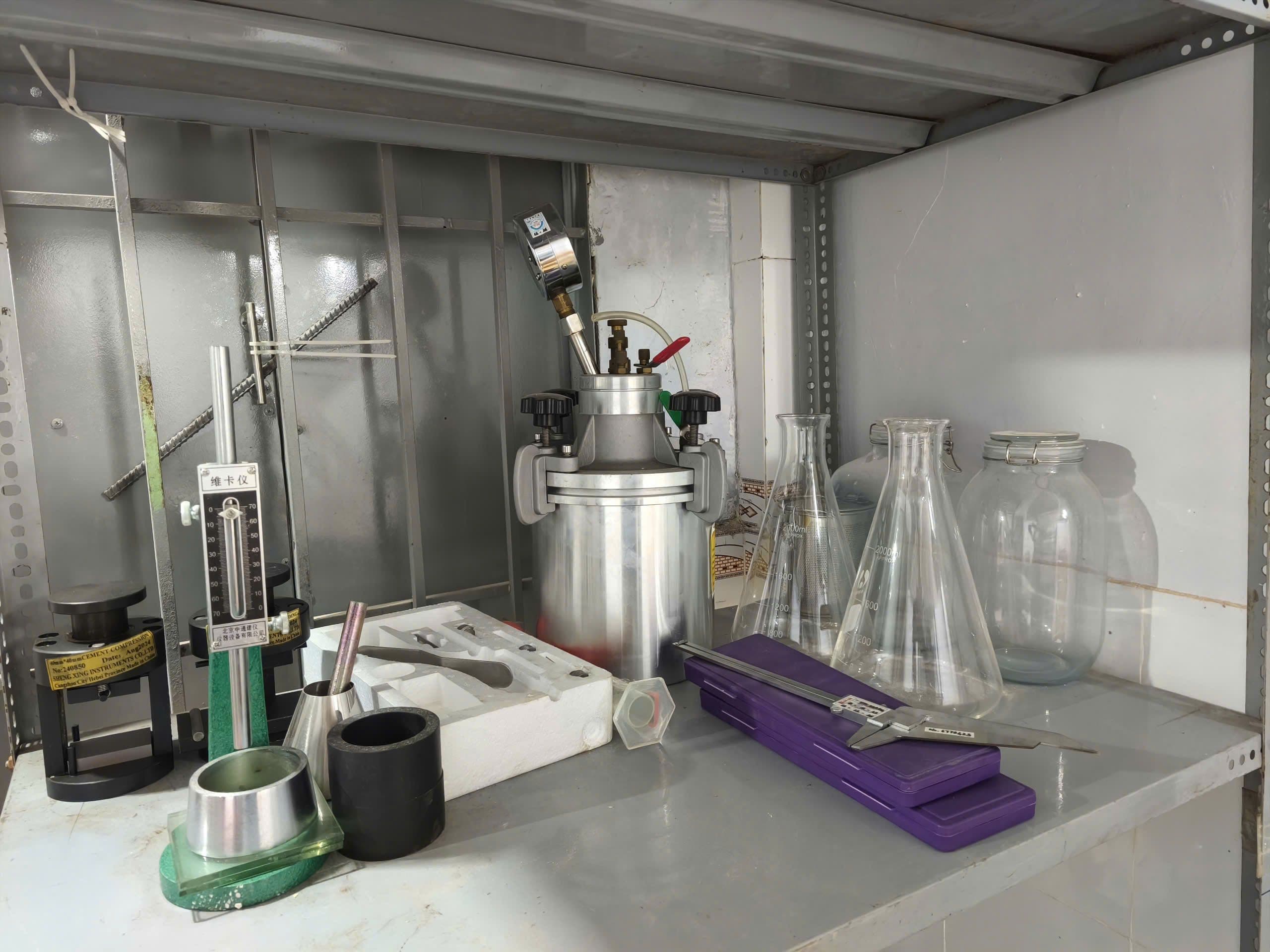 Various laboratory equipment, including flasks, beakers, and a metal pressure vessel on a shelf.